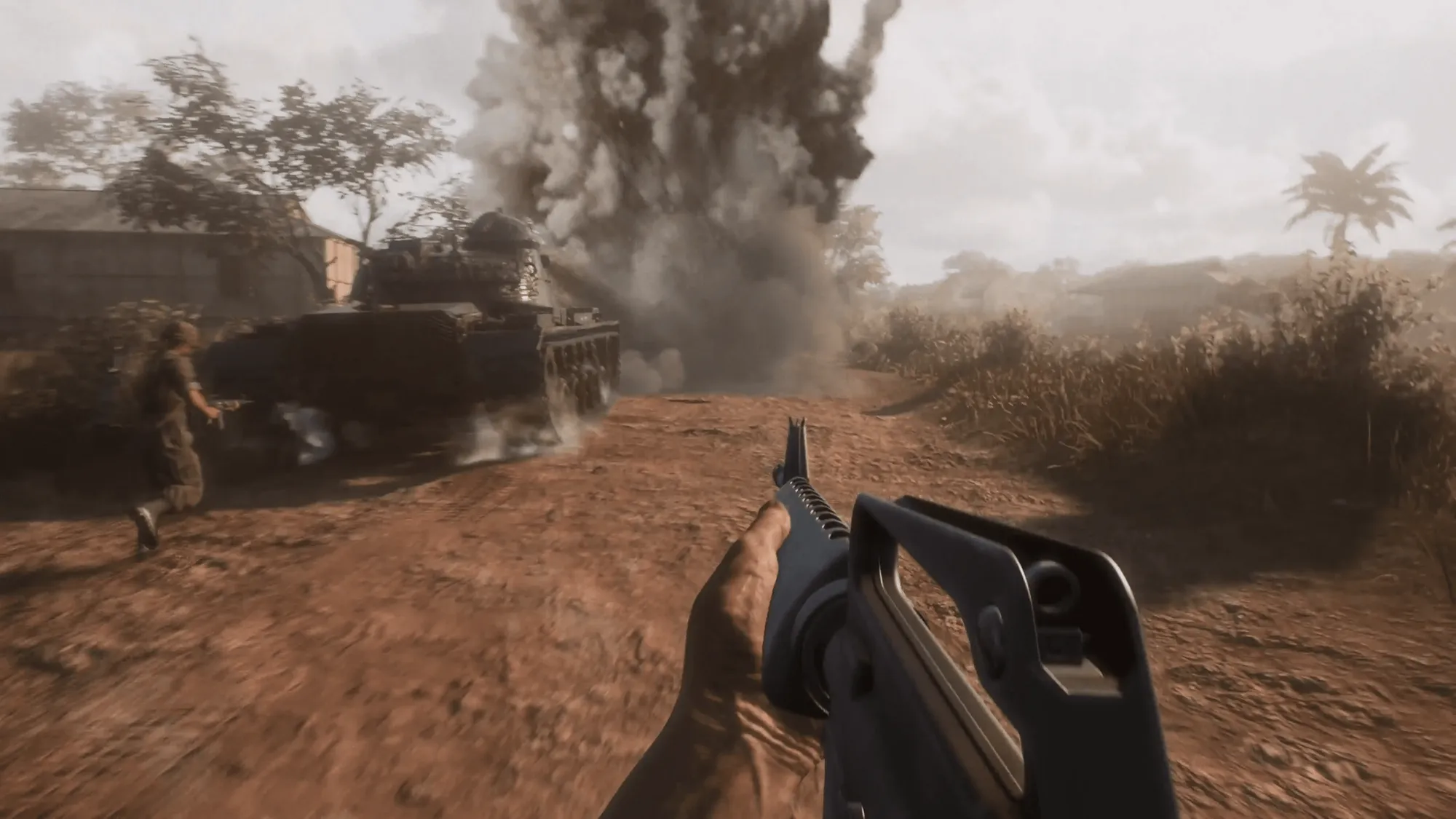 First-person soldier view beside a tank as a large explosion rises on a rural Hell Let Loose Vietnam battlefield